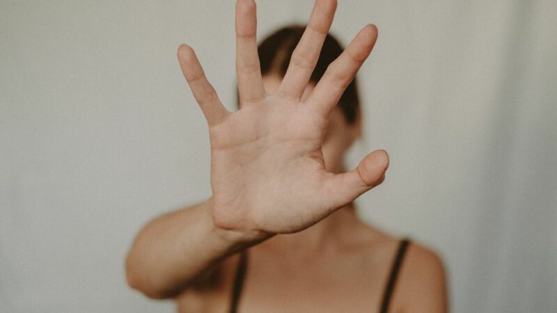 Mulher com a palma da mão aberta indicando "pare".