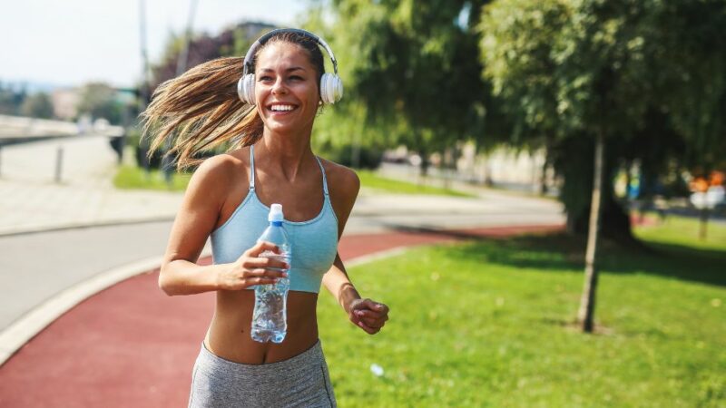 Mulher correndo segurando garrafa de água.